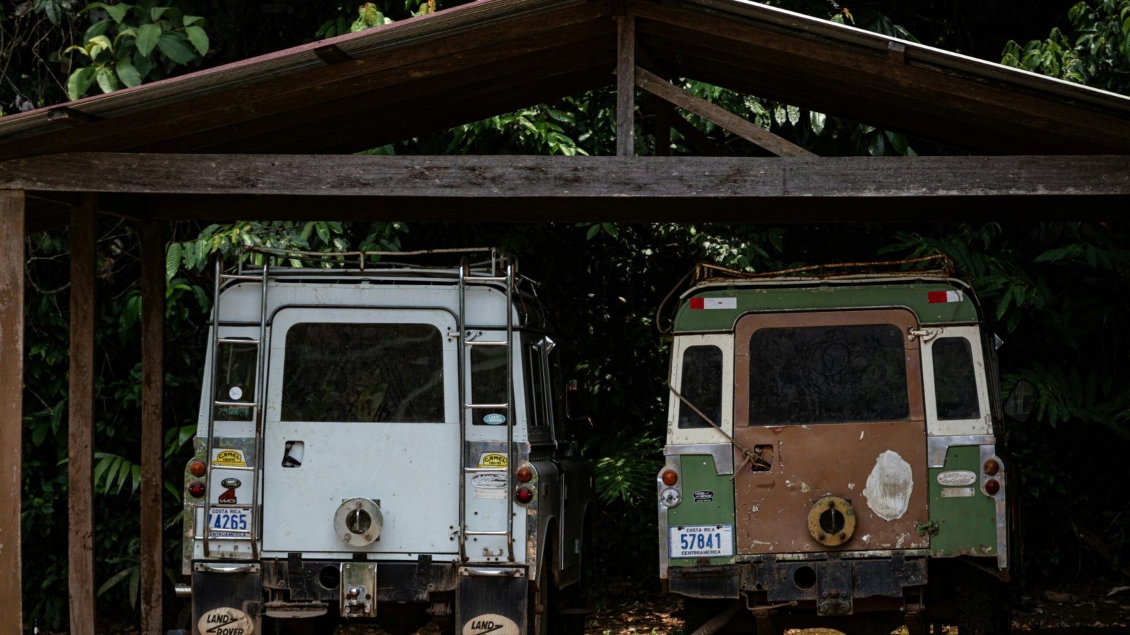 A couple of trucks parked under a wooden structure